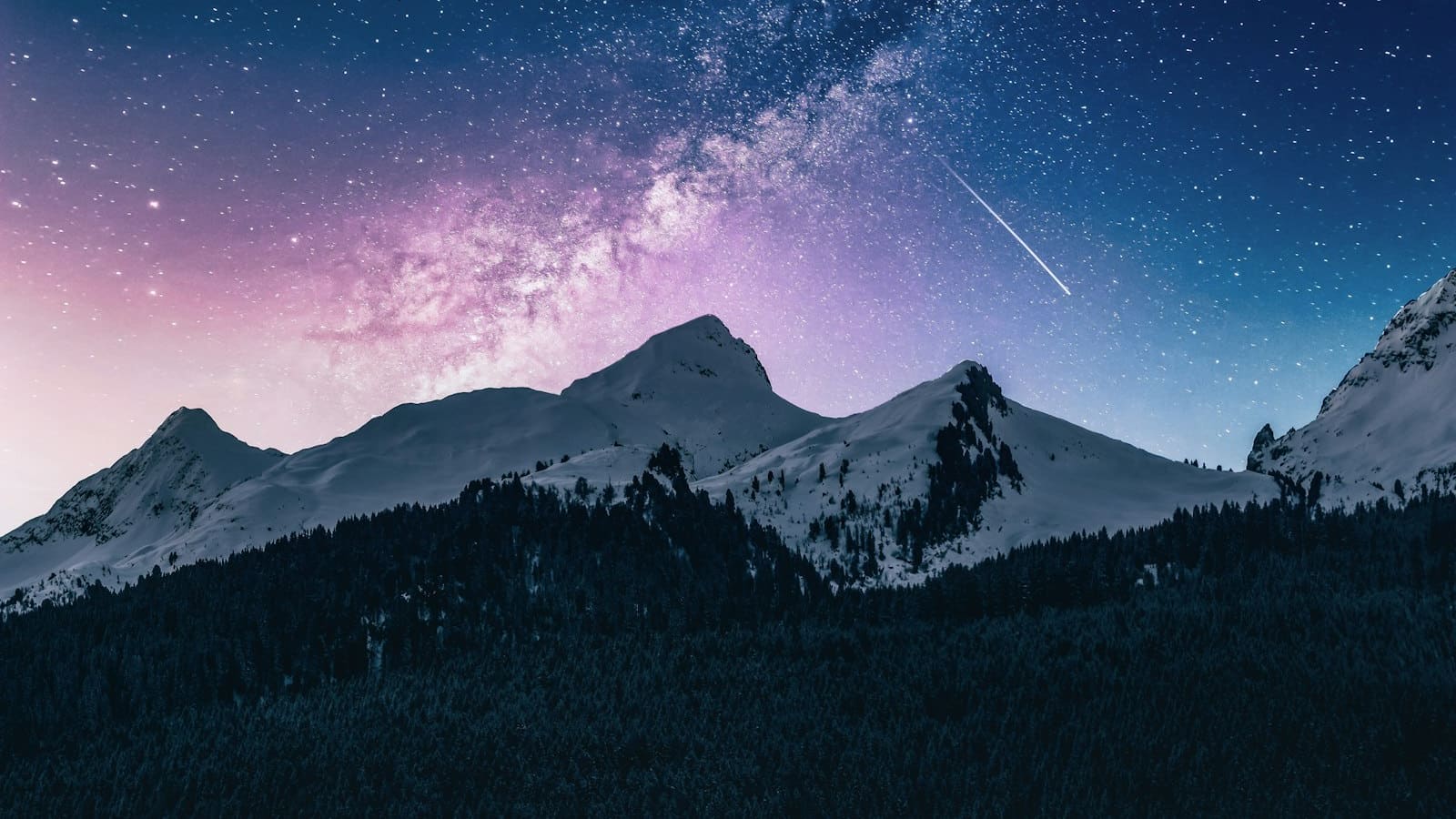 The Milky Way and a shooting star over dark mountain ridgelines at night