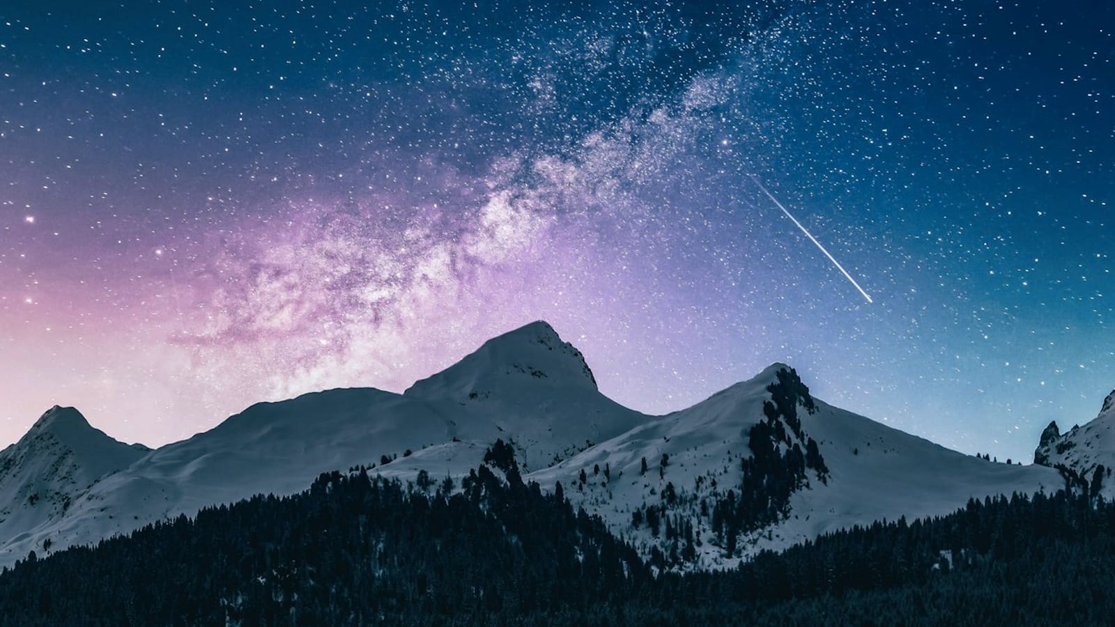 The Milky Way and a shooting star over dark mountain ridgelines at night