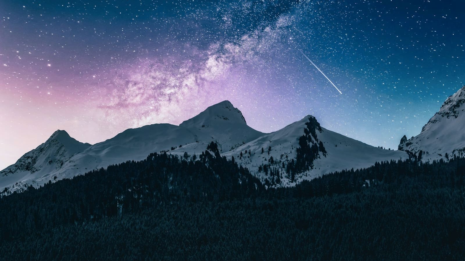 The Milky Way and a shooting star over dark mountain ridgelines at night